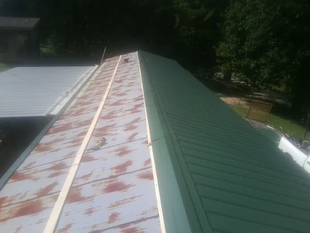 Old rusted panels beside newly installed green metal roofing — Wind Damage Roof Repair by Roofing Brothers in Rockford